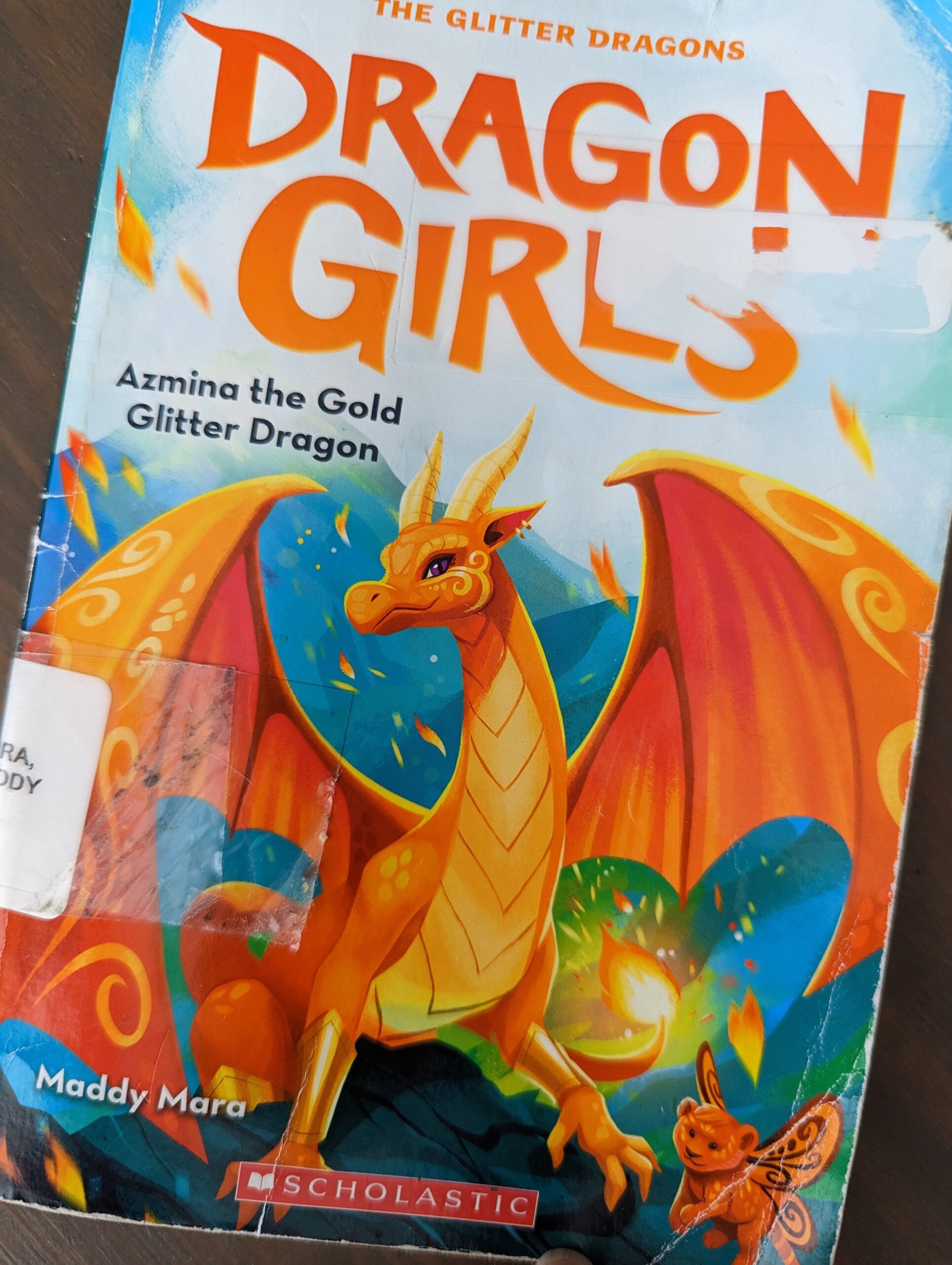 Book cover for the first book in the Dragon Girl series "Azmina the Gold Glitter Dragon" by Maddy Mara